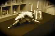Unser Sarg, mit kreuzfrmigem Blumenkranz, Kerzen und einem Bild des Verstorbenen.