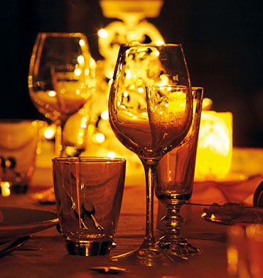 Closeup eines gedeckten Tisches bei einem Gastronomie-Partner mit Fokus auf Getränkegläsern mit warmer Lichtstimmung