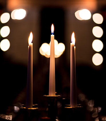 Closeup von drei Kerzen und verschwommenen Lichtern im Hintergrund
